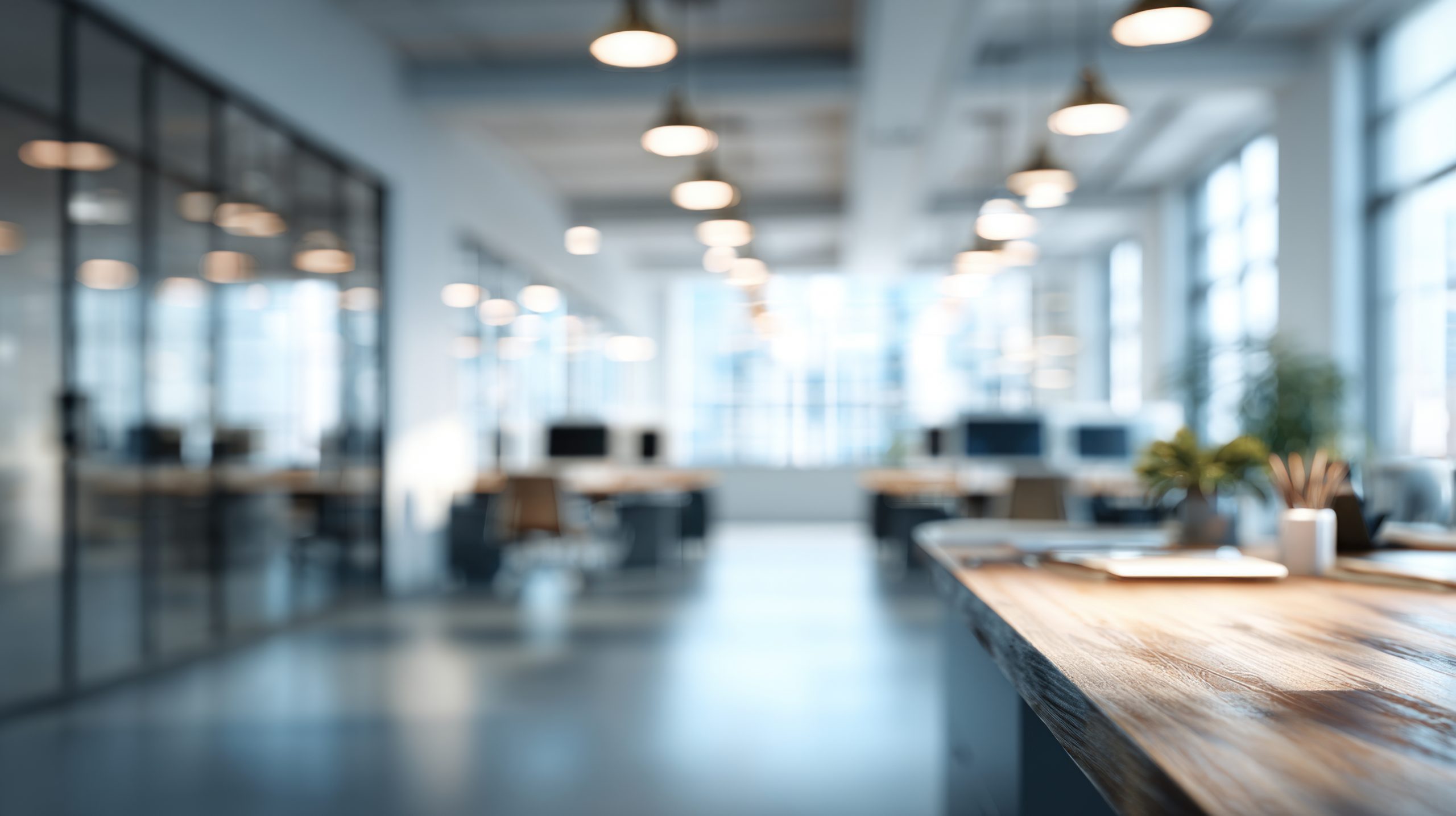 Moderner Büroarbeitsplatz mit offenen Schreibtischen, Glaswänden, Holzoberflächen und heller Beleuchtung