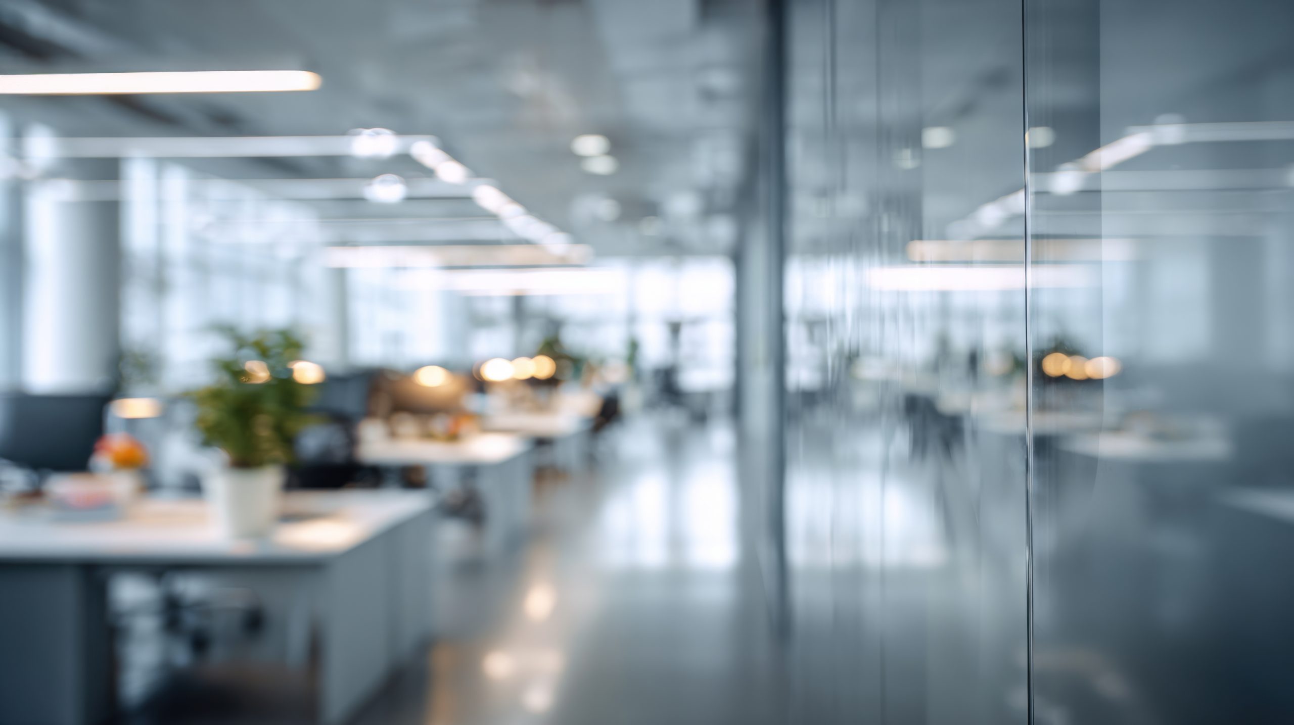 Moderner Büroarbeitsplatz mit Glaswänden, offenen Schreibtischen und heller Beleuchtung